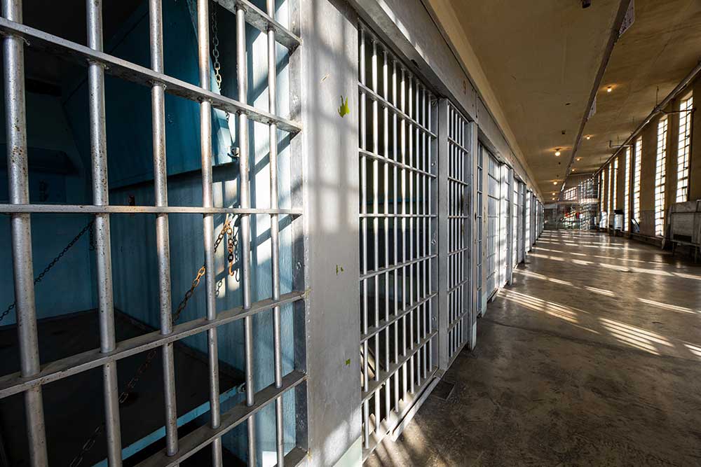 Sun and shadows form on the bars of a prison